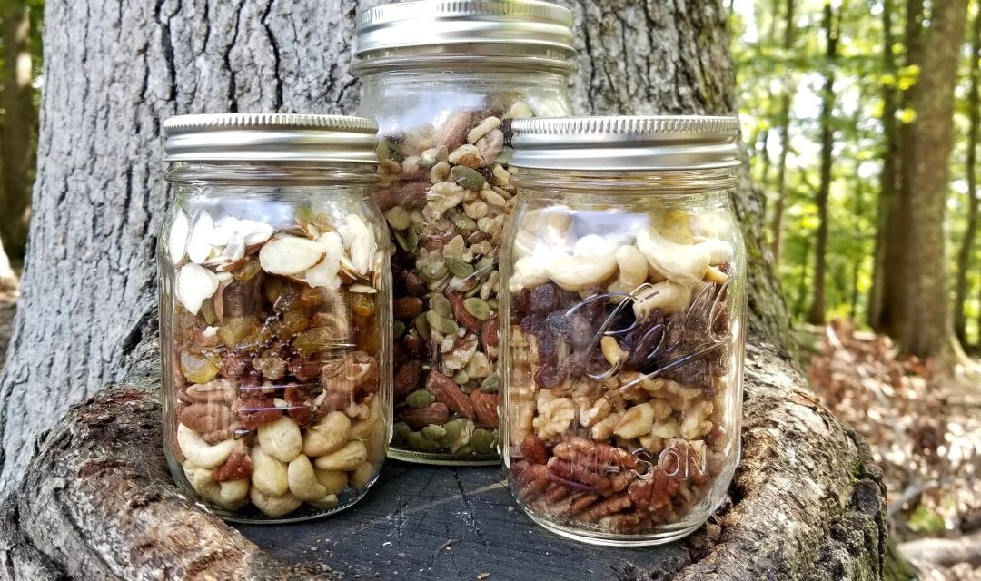 Paleo trail mix in mason jars displayed on a tree stump
