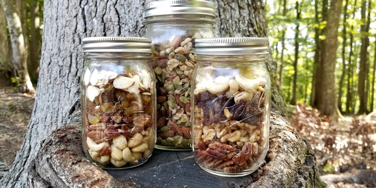 Paleo trail mix in mason jars displayed on a tree stump