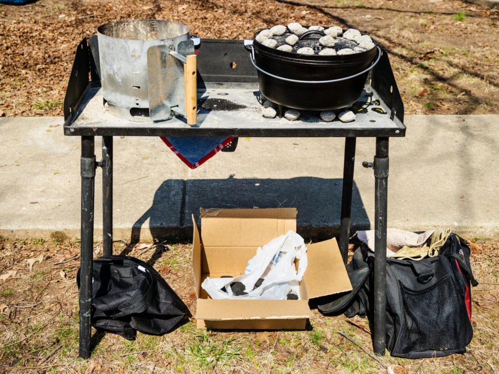 a dutch oven sitting on a bed of charcoal on a dutch oven table 