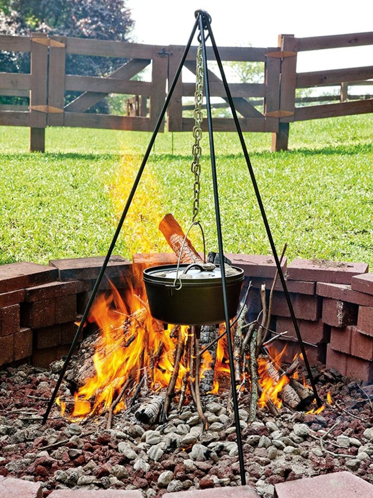 dutch oven hanging from a tripod over the campfire