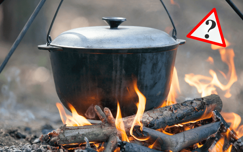 dark colored enameled dutch oven hanging over a campfire with a question mark in the upper right hand corner