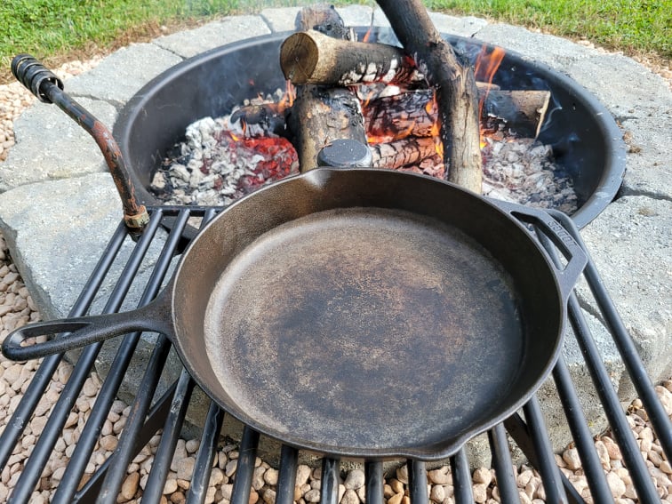 Heating cast iron skillet by the campfire to completely dry it 