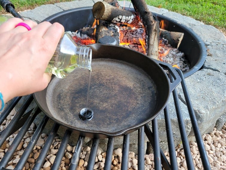 Pouring a small amount of oil into a cast iron skillet for seasoning