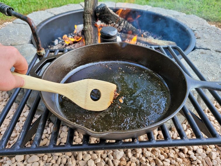 https://campfiresandcastiron.com/wp-content/uploads/2021/07/Scraping-Food-Residue-Out-Of-Skillet-With-Wooden-Spoon.jpg