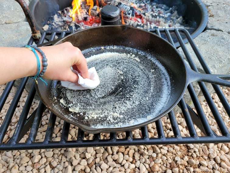 Scrubbing a dirty cast iron skillet with salt and a paper towel 