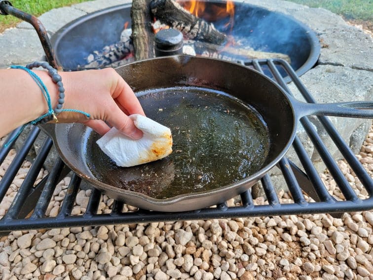 Wiping grease out of a cast iron skillet with a paper towel 