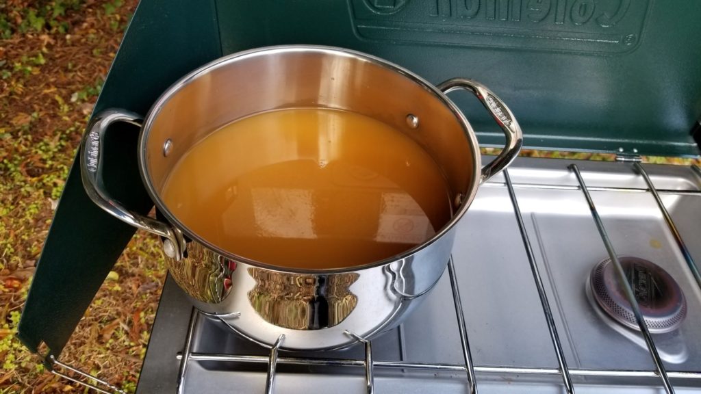 apple cider in a stainless steel stockpot over a camping stove