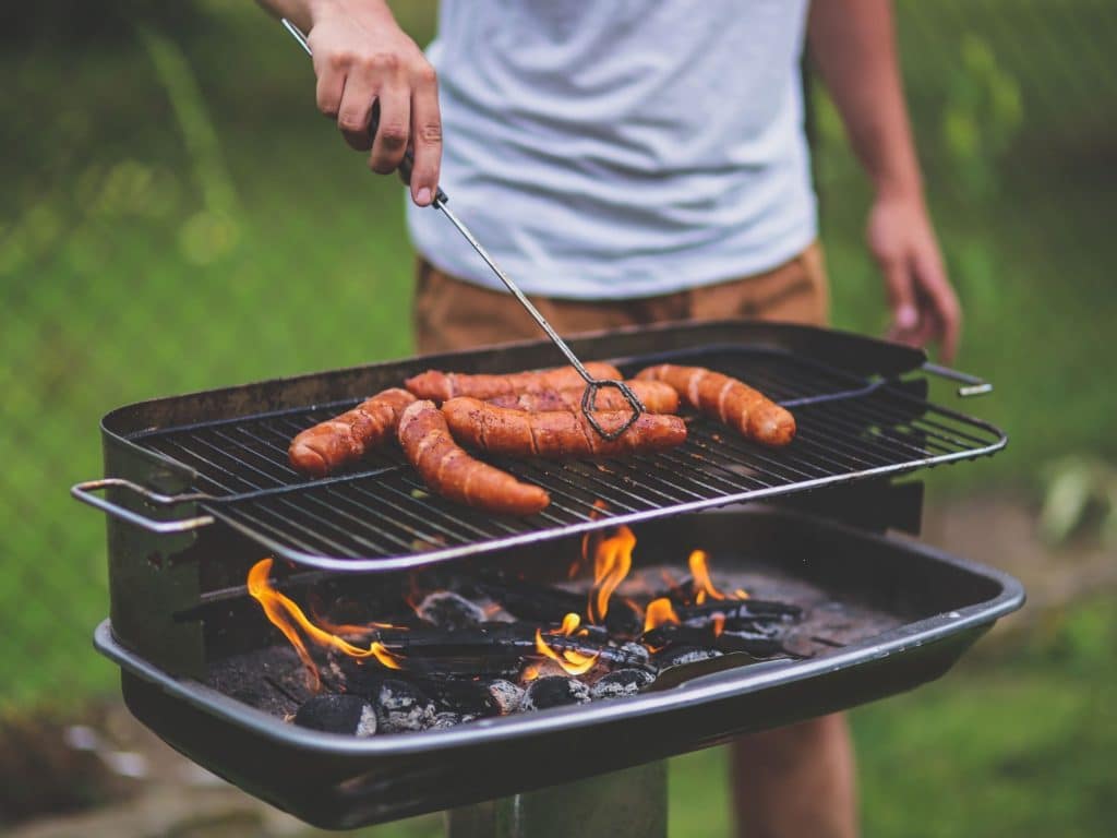 cooking hot dogs on a charcoal camp grill 