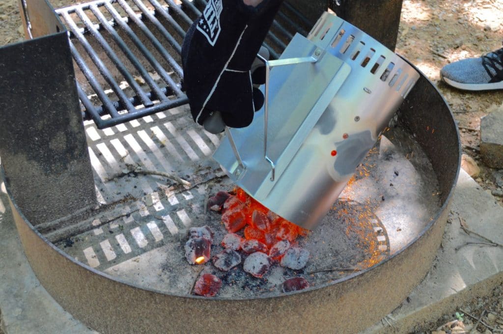 dumping the red-hot charcoal into the fire pit while wearing heat-resistant gloves