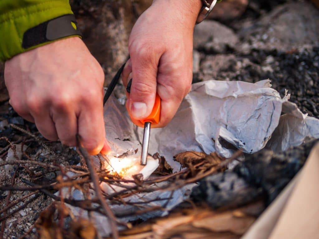 using a flint stick to light a campfire