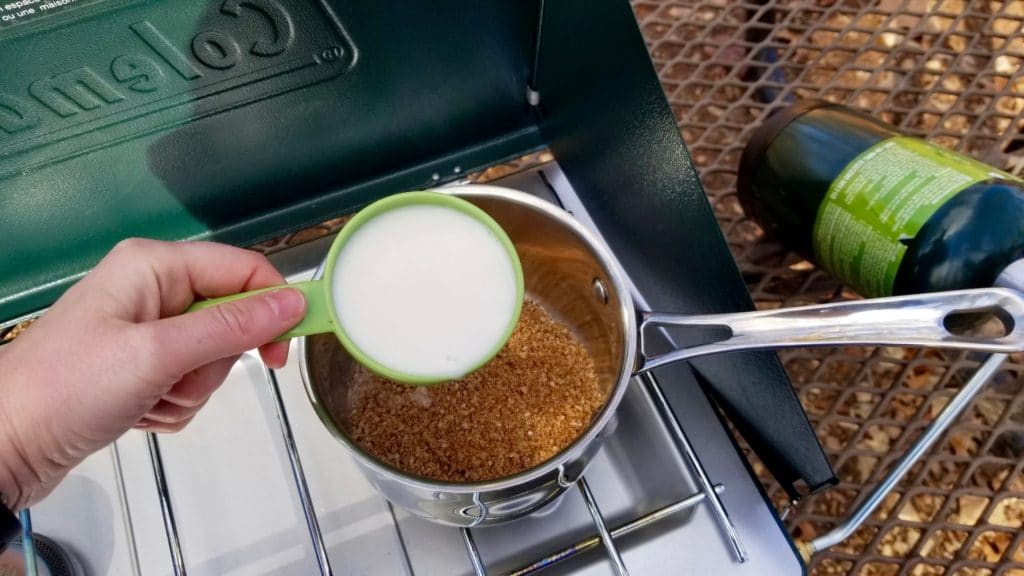 mixing non-dairy milk with paleo oatmeal mix in a saucepan on a camping stove