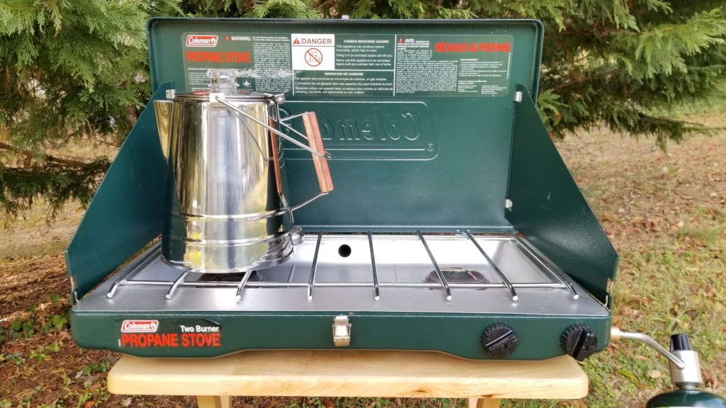 stainless steel percolator sitting on a camping stove burner