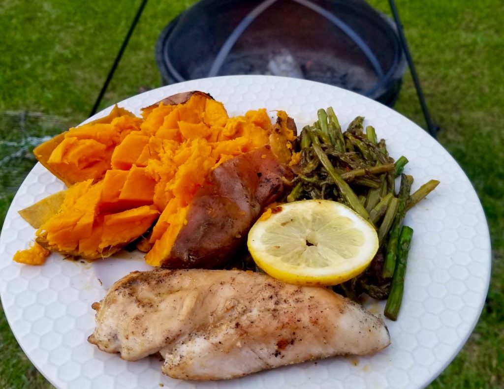 campfire lemon chicken and asparagus with a sweet potato on a white plate 