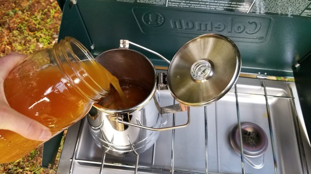 pouring apple cider into a camping percolator pot 