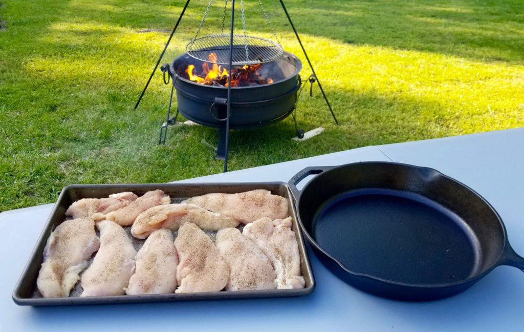 seasoned chicken breasts on a tray ready to be cooked over a fire pit 