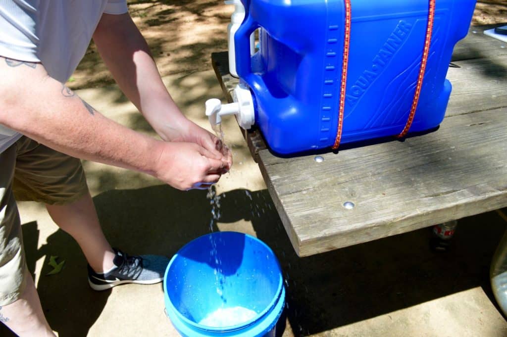 a person washing their hands at the camping handwashing station 