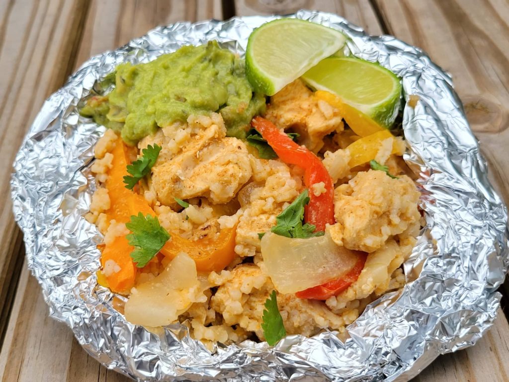 Chicken Fajita and Rice Foil Packet garnished with guacamole and lime wedges