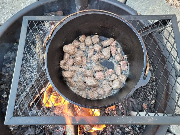 browning stew beef in a dutch oven over the campfire