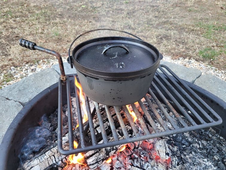 dutch oven on a metal grate cooking over a campfire