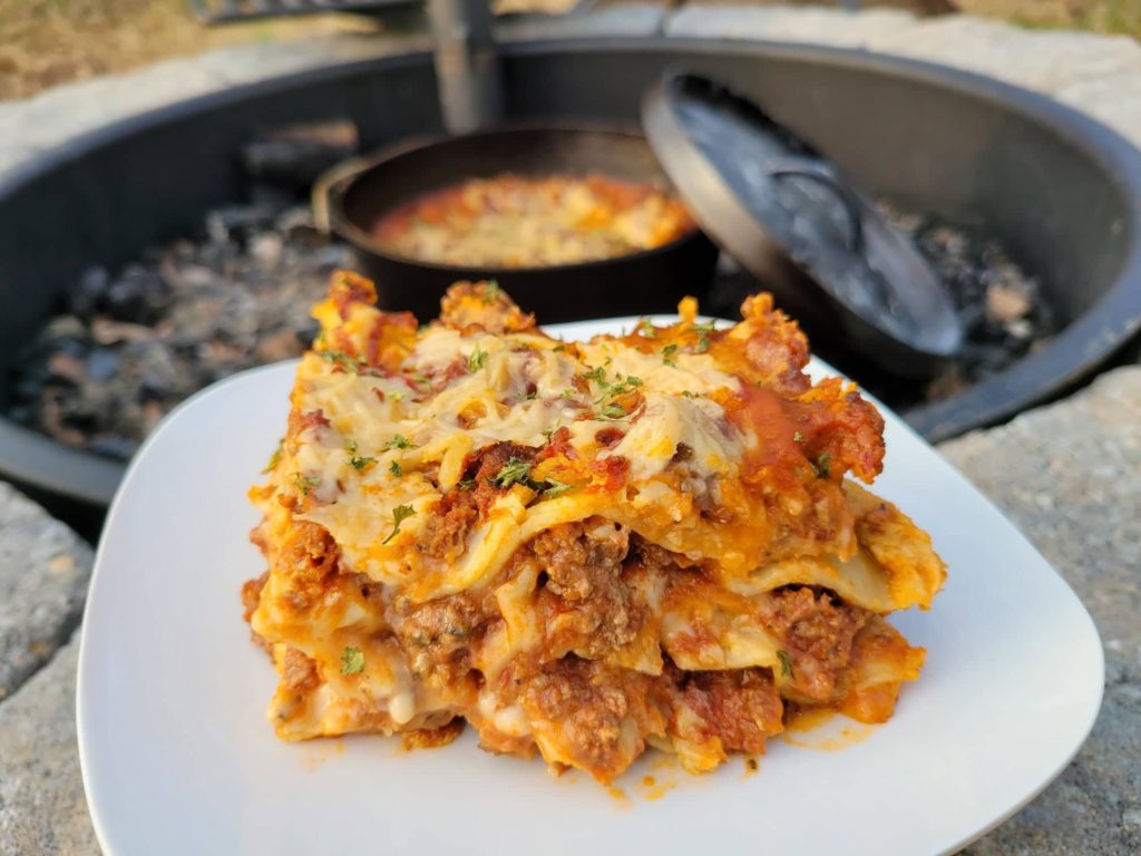 Dutch oven lasagna on a plate by the fire pit 