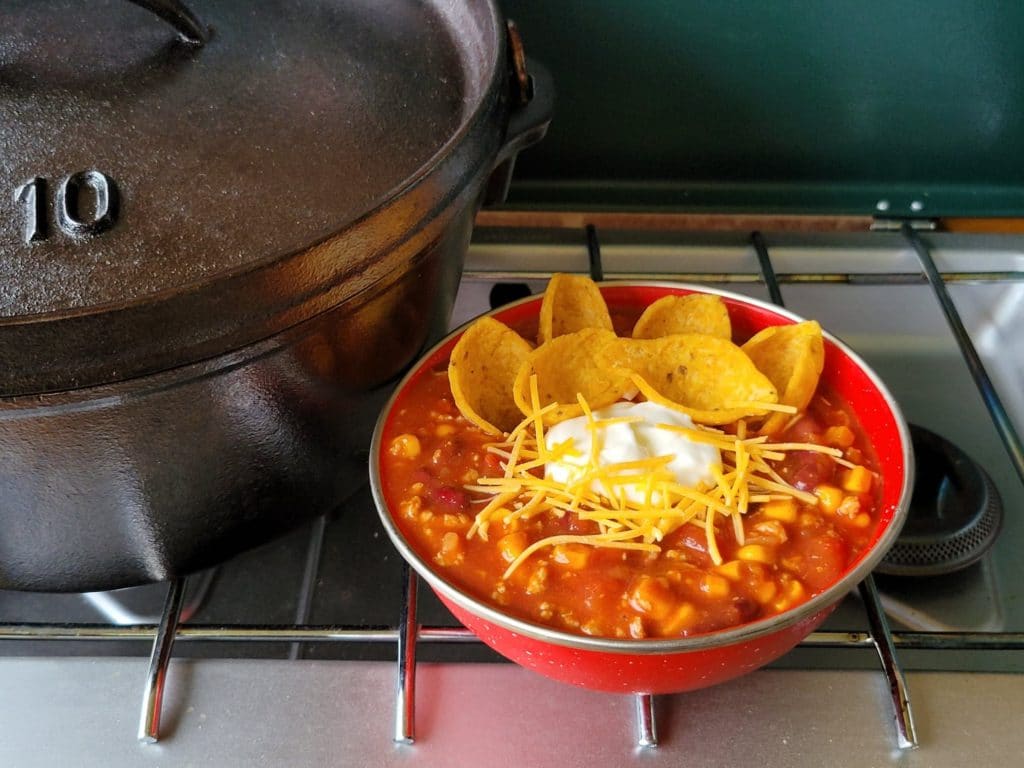 Easy Dutch Oven Taco Soup in a red bowl on a camping stove