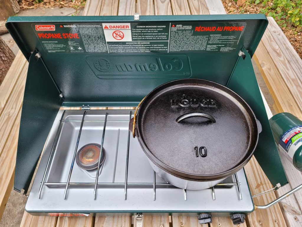 preheating the dutch oven on a camping stove 