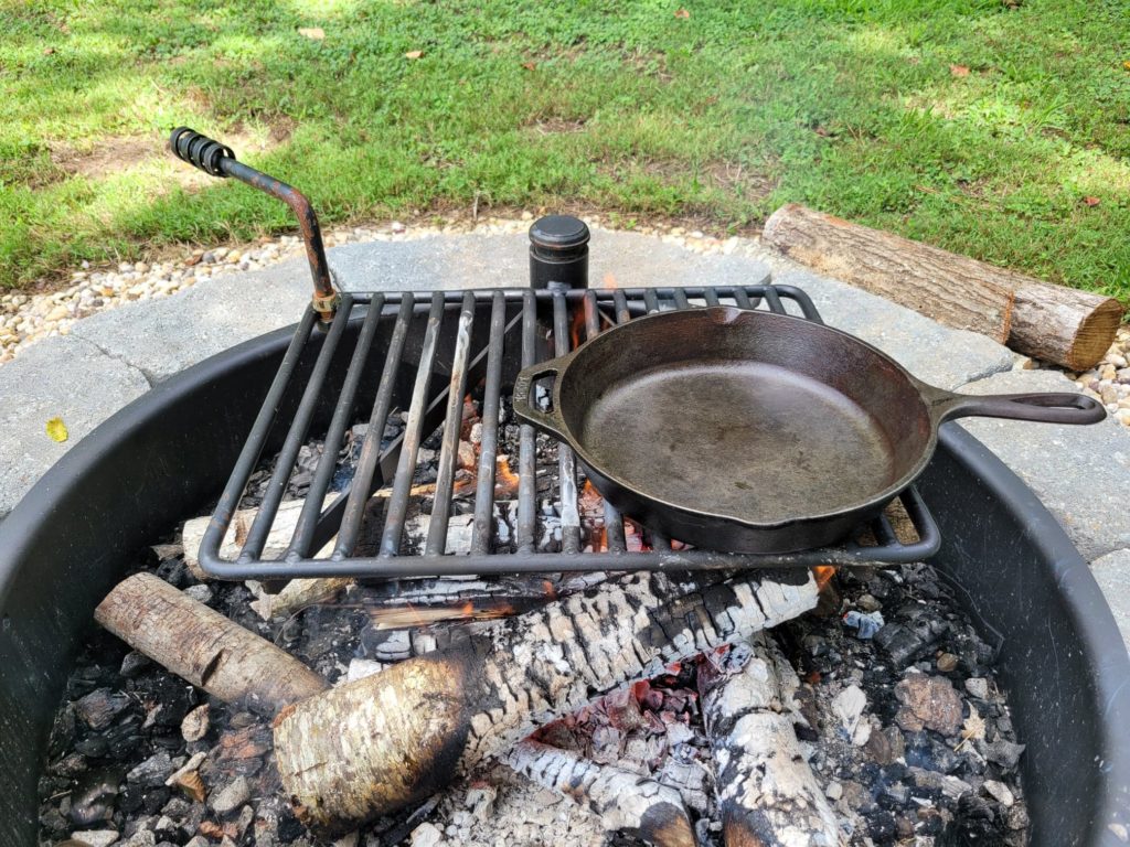 cast iron skillet on a built-in fire pit cooking grate
