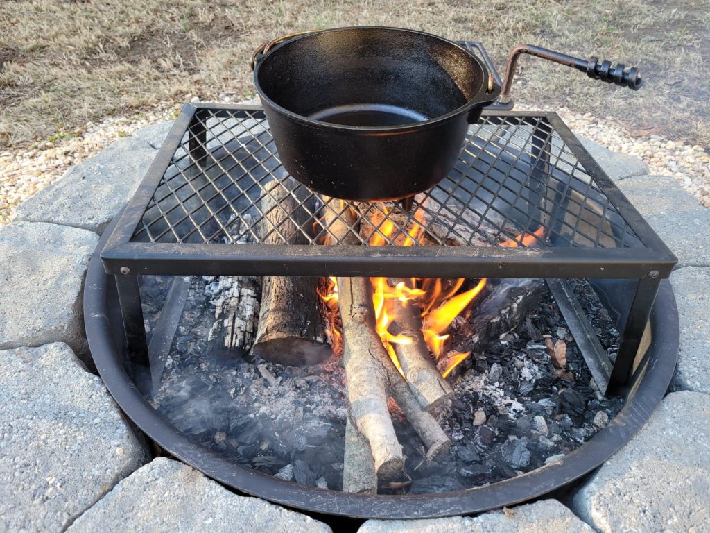 cast iron dutch oven on a campfire cooking grate