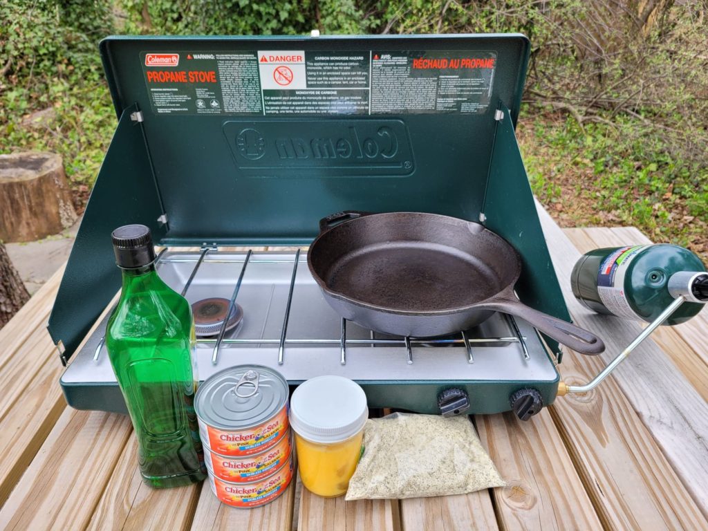 camping stove, cast iron skillet, and ingredients for salmon patties 
