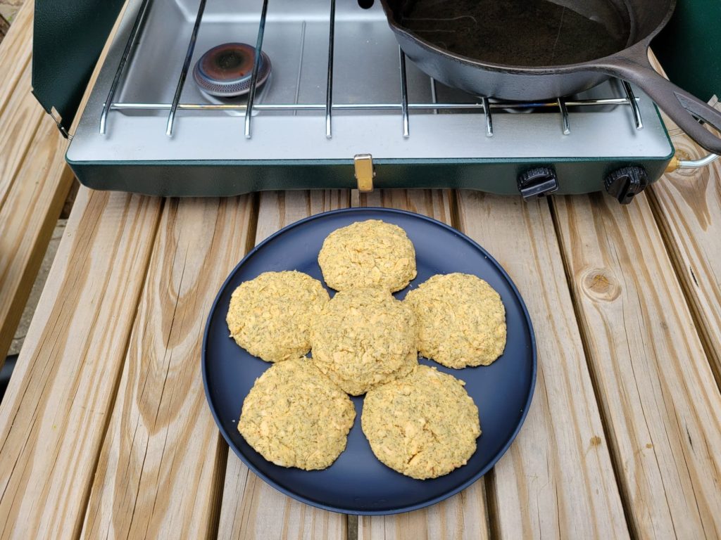 Uncooked salmon patties on a plate in front of the camping stove