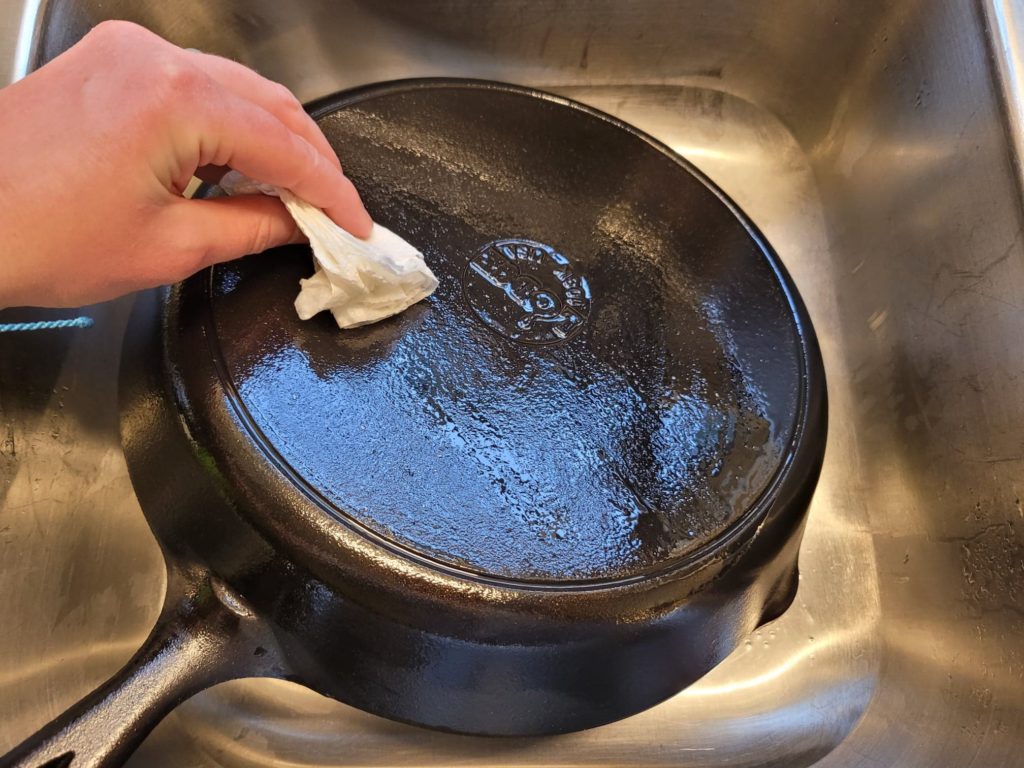 Wiping vegetable oil all over a cast iron skillet to remove soot