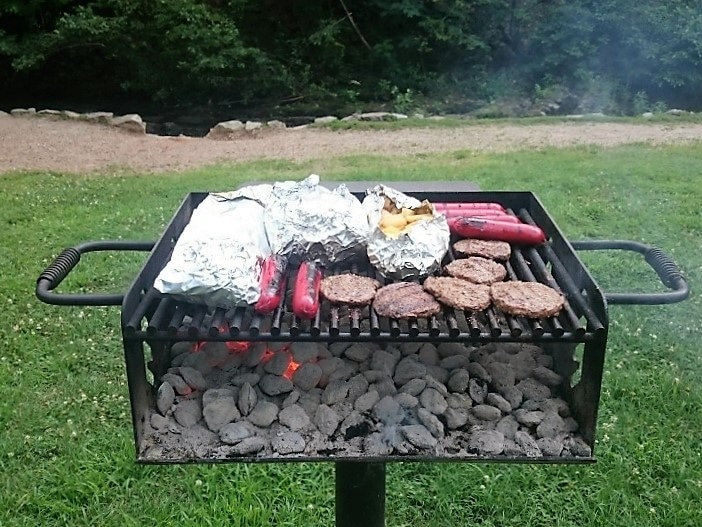 Foil packets cooking on a campground charcoal grill