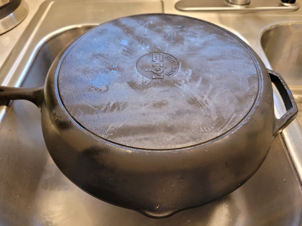 Dirty, soot-covered cast iron skillet in a sink. 