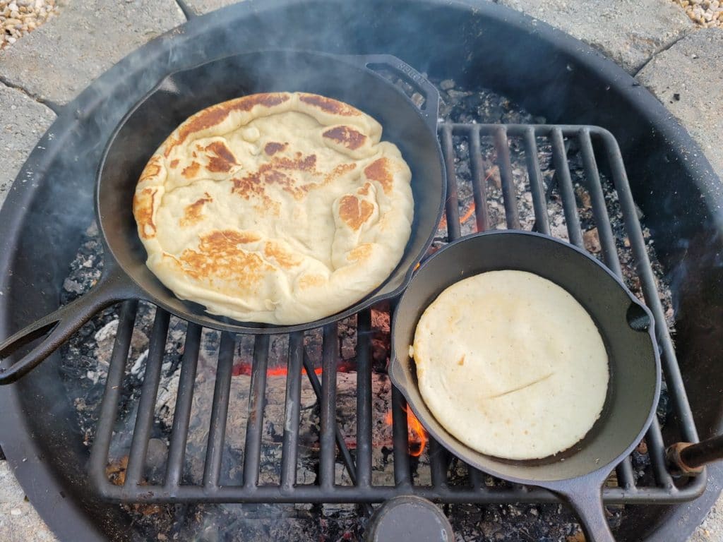 cooking the other side of the pizza dough over the campfire
