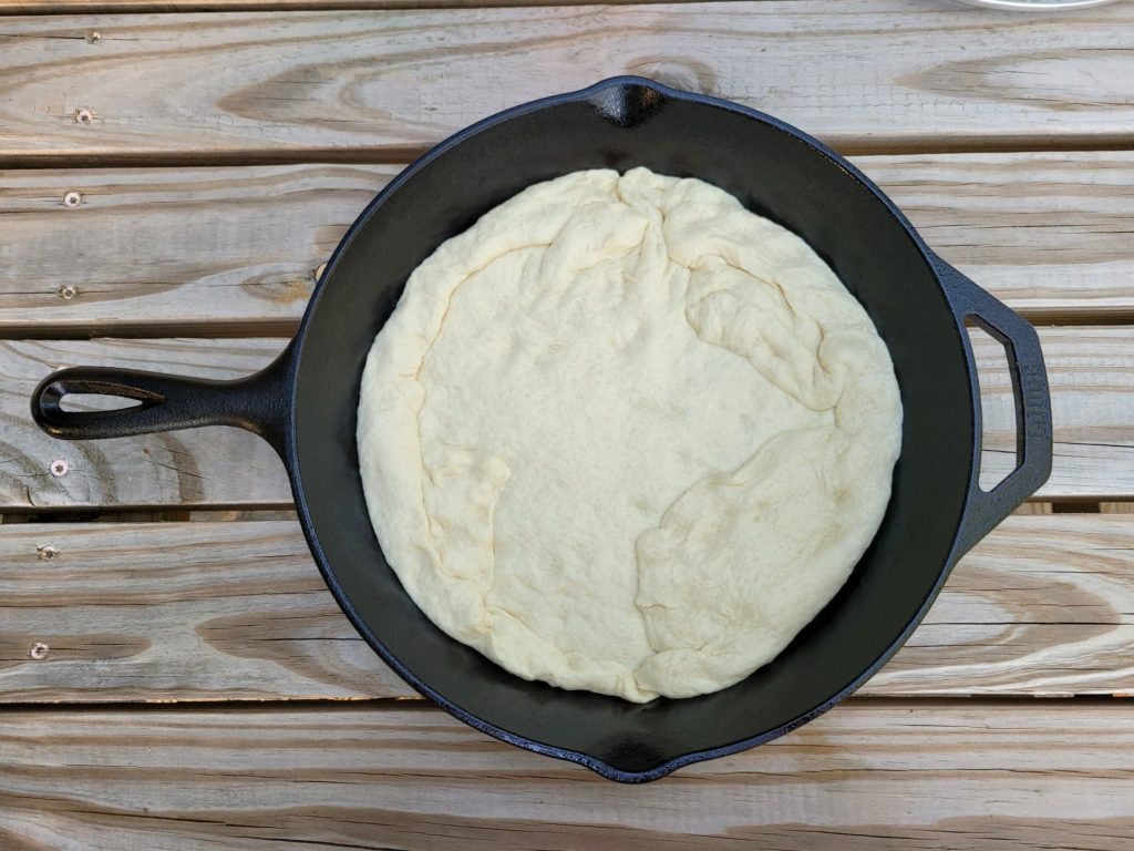 uncooked pizza dough in a cast iron skillet 