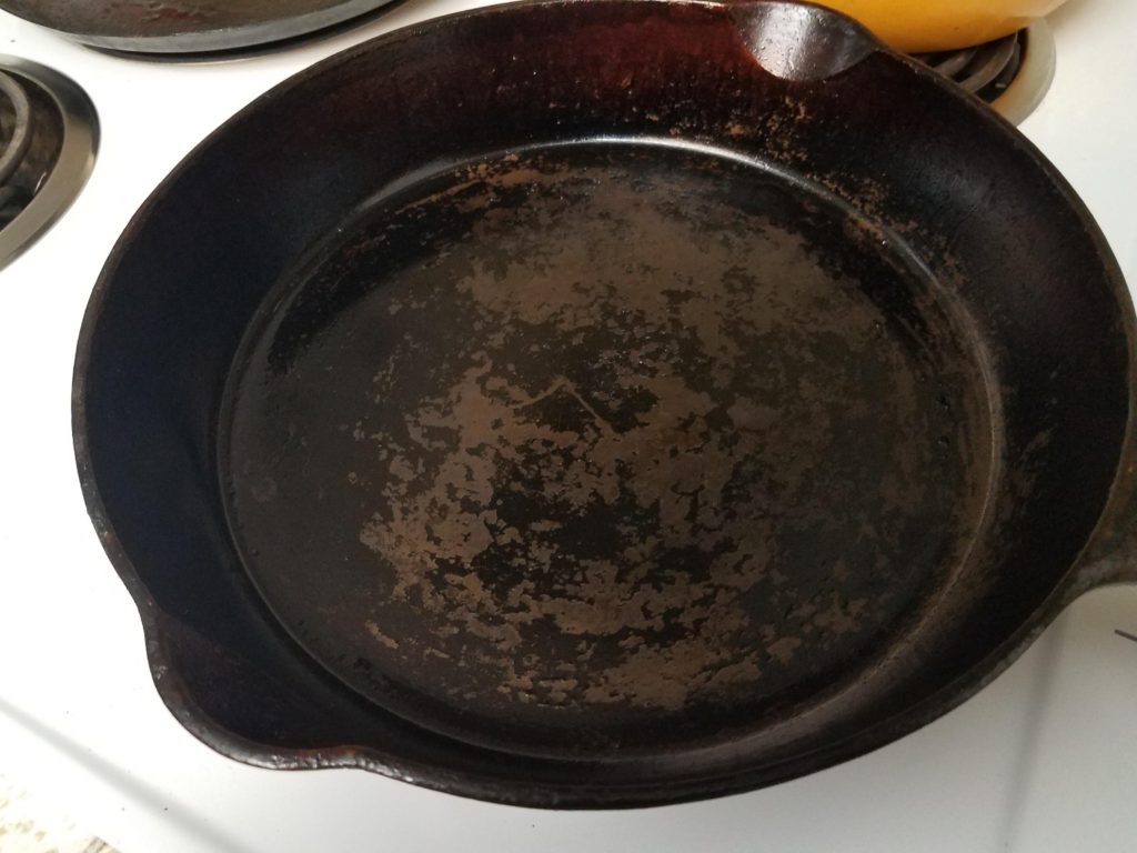 cast iron skillet with flaking seasoning on a stovetop