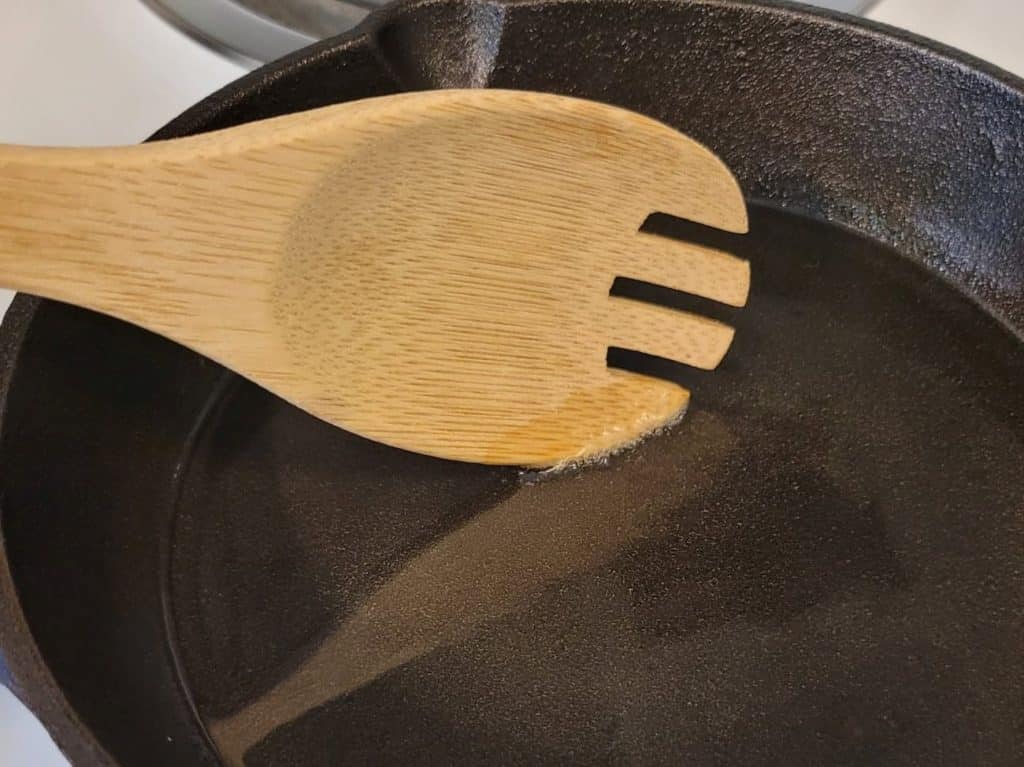 hot oil bubbles forming around a wooden spoon edge in a pan