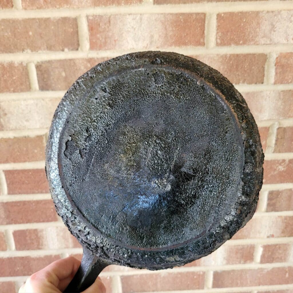 Unrestored cast iron pan covered in carbon buildup 