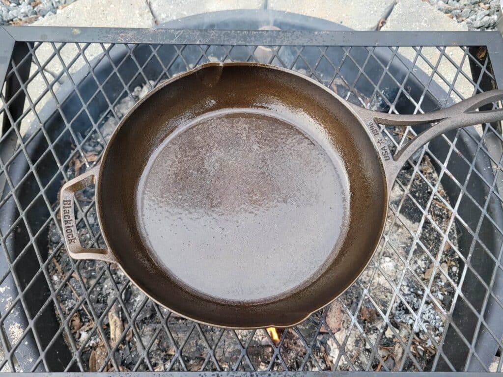 Cast iron skillet over campfire sprayed with cooking spray